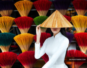 Nón lá truyền thống Việt Nam, nữ model mặc áo dài, đứng giữa quạt màu sắc rực rỡ.