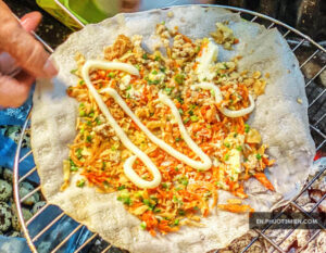 bánh tráng cuốn với tôm, rau củ và sốt mayonnaise, đang được nướng trên vỉ.