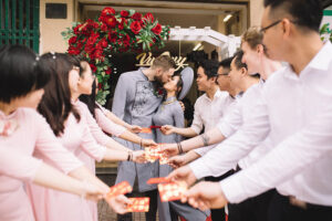 Cặp đôi vui vẻ trong lễ cưới Việt Nam, cùng bạn bè cầm thiệp mời trong khung cảnh trang trí lãng mạn.