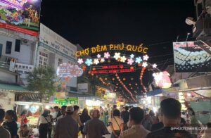 Chợ đêm Phú Quốc với ánh đèn rực rỡ, người dân và du khách tham quan, mua sắm giữa không gian sôi động.