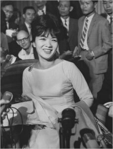 madame nhu trong buổi họp báo, tươi cười và tự tin giữa đám đông phóng viên.